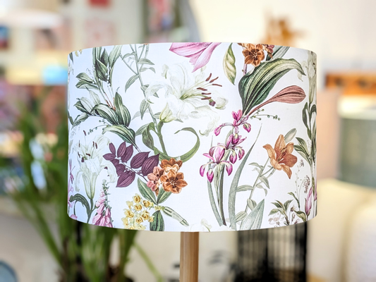 The Emotive Collection’s Summer Floral Lampshade features a handcrafted design with vibrant flowers and green leaves on a white background, adding an Australian-made touch to any softly blurred indoor setting.