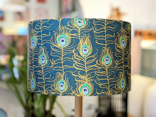 Handmade Peacock Feather Nouveau lampshade by Emotive Collection, featuring a luxurious peacock feather design in gold tones on a blue background. Designed by Australian artist Cecilia Mok. Crafted in Australia.