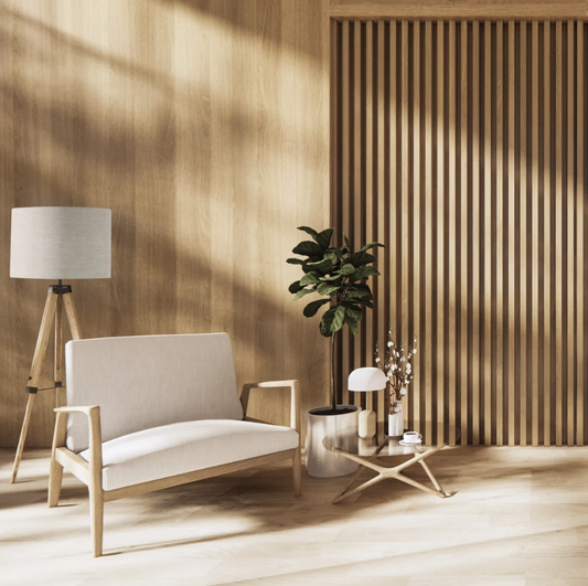 Minimalist living space with light wood walls, a beige loveseat, small round table with decor, potted plant, and sunlight. The Emotive Collection Stone Premium Linen Lampshade on a tripod floor lamp adds calm and modern style.