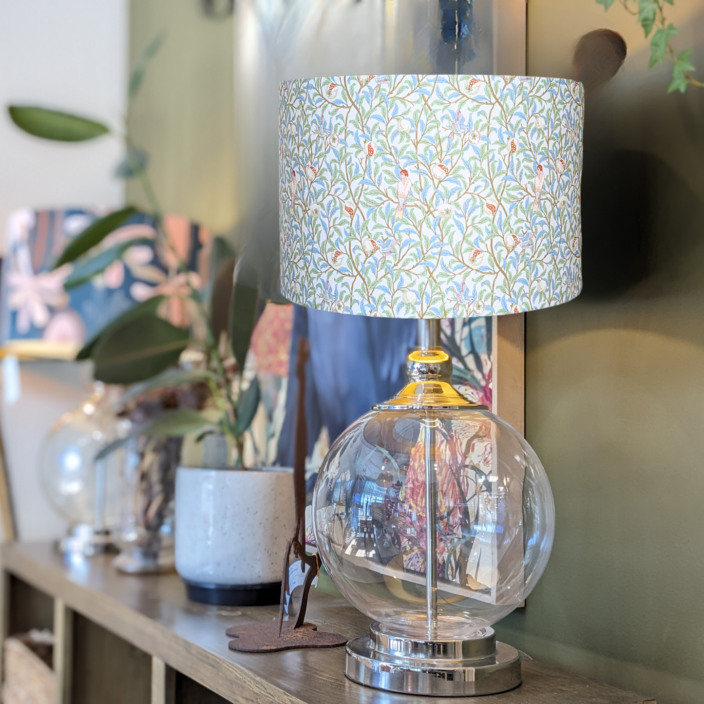 Side view of the Bird & Pomegranate lampshade on a glass lamp base, featuring intricate bird and pomegranate patterns in the iconic William Morris style. Crafted in Australia.