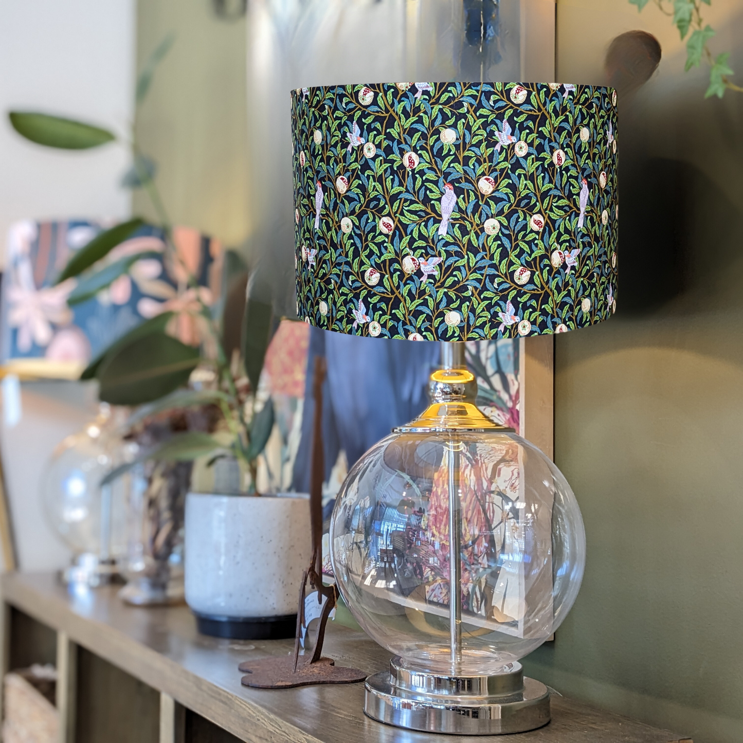 Elegant Bird & Pomegranate Black William Morris lampshade on a glass lamp base, with vivid colors and a bold black background, handcrafted in Australia to add a touch of luxury to your décor.