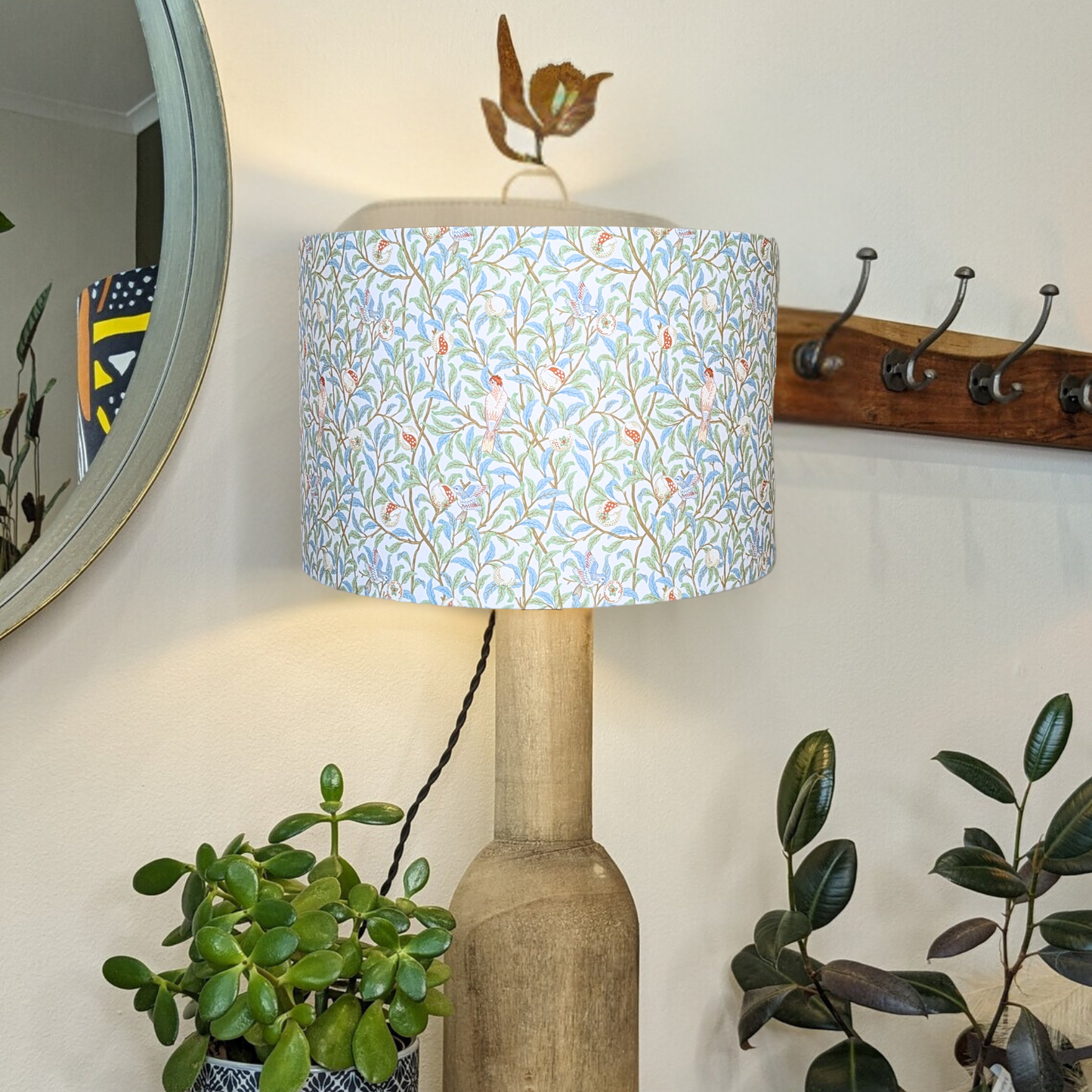 Handcrafted Bird & Pomegranate William Morris lampshade on a wooden base with the light turned on, featuring intricate birds and pomegranate motifs. Expertly made in Australia by Emotive Collection.