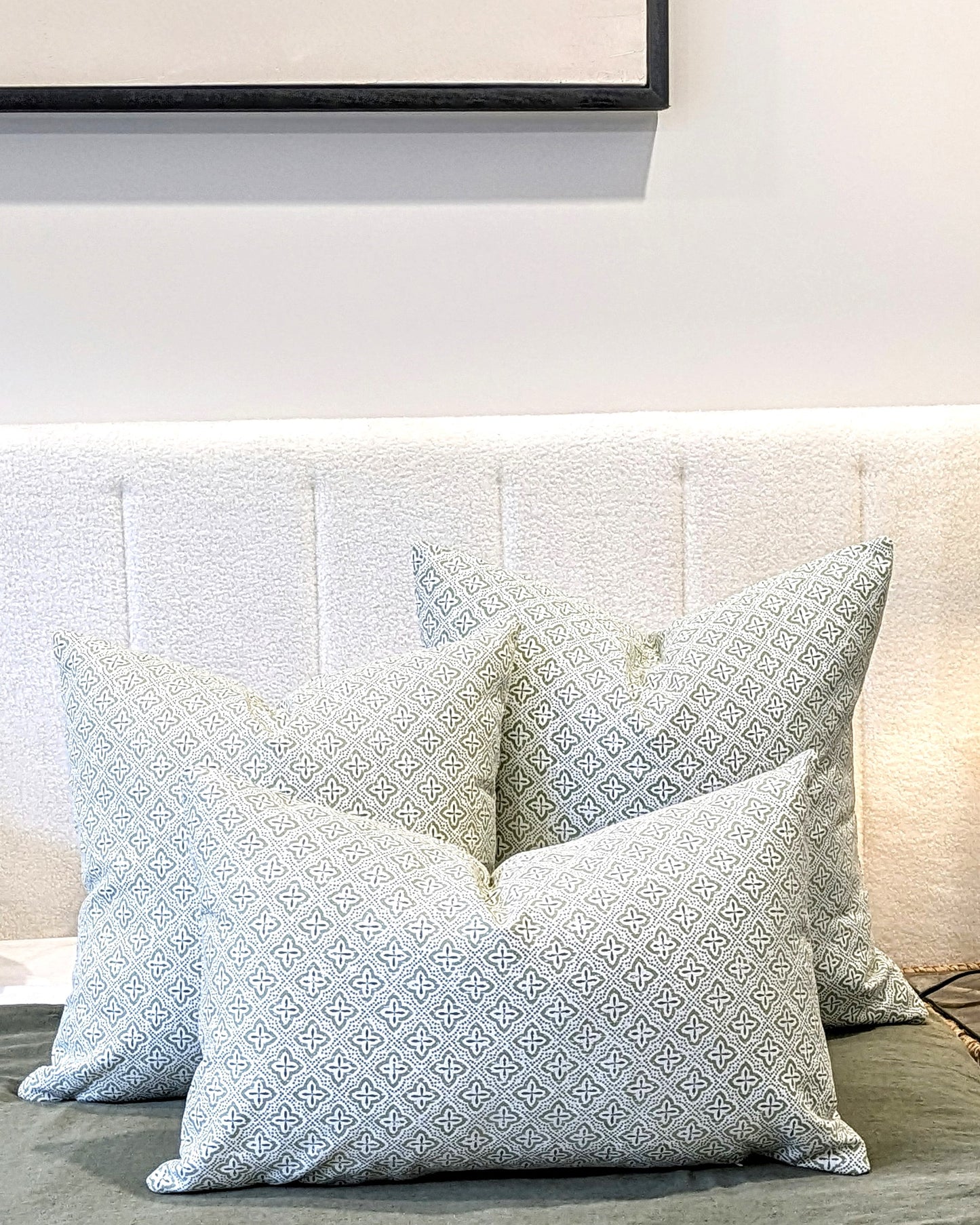 Four Emotive Collection Tiles Cocoon Cushion Covers, featuring a subtle geometric pattern and handmade quality, are neatly arranged on a light upholstered headboard, creating a cozy and inviting bedroom atmosphere.