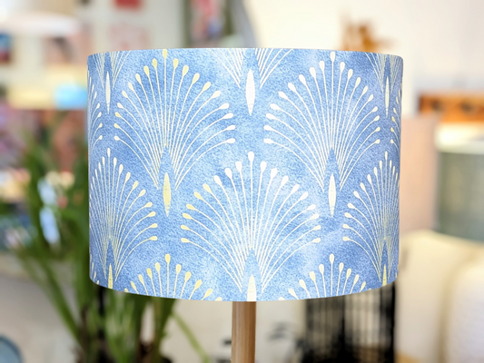 A close-up of the Art Deco Gatsby Lampshade (35cm x 24cm) features a blue background with a white and yellow fan pattern, its striking design highlighted against a softly blurred backdrop. Australian made.