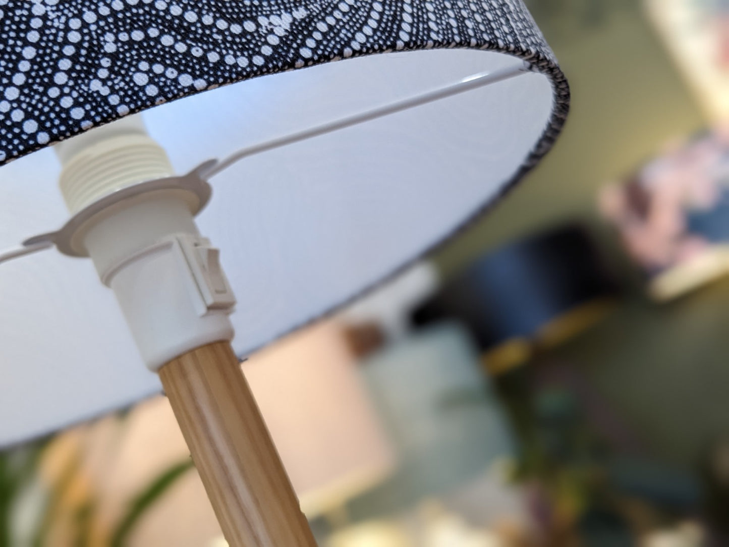 Close-up of the Desert Dreaming Aboriginal lampshade by artist Senita Napangardi Granites, featuring a black-and-white dotted pattern inspired by Desert Fringe-Rush Seed Dreaming. Wooden lamp stand; another lamp is blurred in the background.