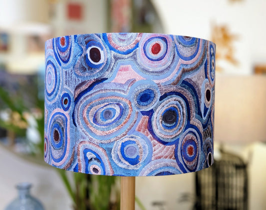 The Aboriginal Water Dreaming Pastel Lampshade by Senita Napangardi Granites features vibrant blue, purple, pink, and white concentric circles in an abstract pattern inspired by Desert Fringe-Rush Seed Dreaming.