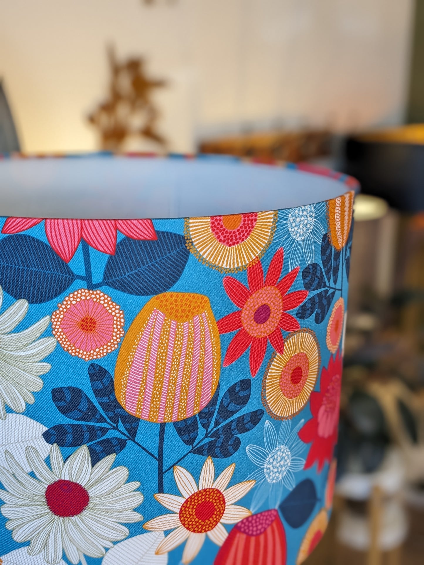 Zoomed in view of the Banksia Grove lampshade, designed by Australian artist Jocelyn Proust, showcasing native Banksia flowers in a beautiful design with flowers on a Blue background. Handcrafted in Australia to add a unique, botanical flair to your space