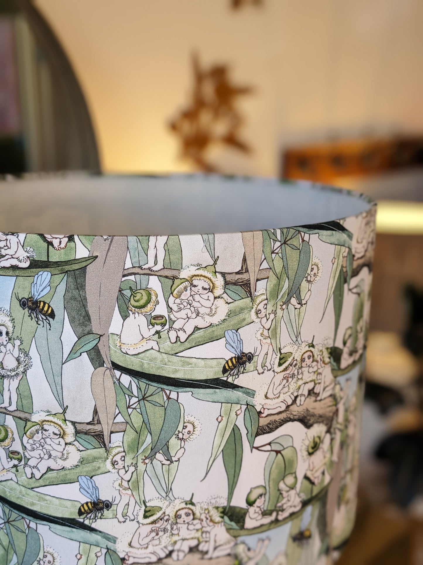Close up of the handmade Vintage May Gibbs lampshade by Emotive Collection, showcasing iconic Australian illustrations of the Gumnuts and Snugglepot on a vibrant yellow base. Crafted in Australia for a whimsical, nostalgic touch to your room.