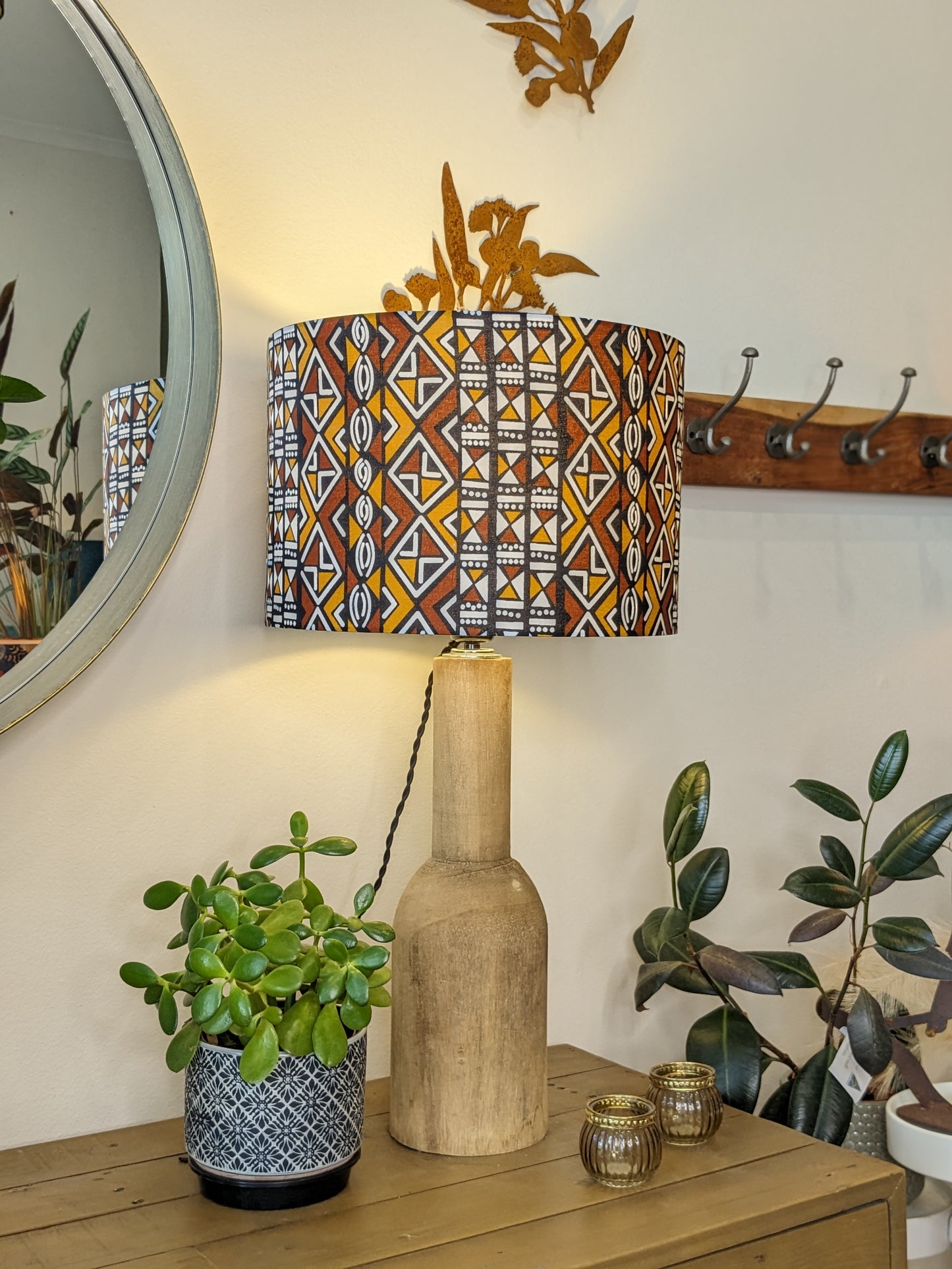 Handmade African Bogolan lampshade by Emotive Collection on a wooden base with the light switched on, featuring traditional African patterns on authentic Bogolan mudcloth fabric. This cultural masterpiece brings an artisan touch to your home décor. Crafte