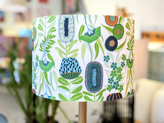The Green Australiana Lampshade by Emotive Collection showcases vibrant green, blue, and orange botanical patterns on white. Proudly Australian Made, it adds a fresh, modern touch to any space.