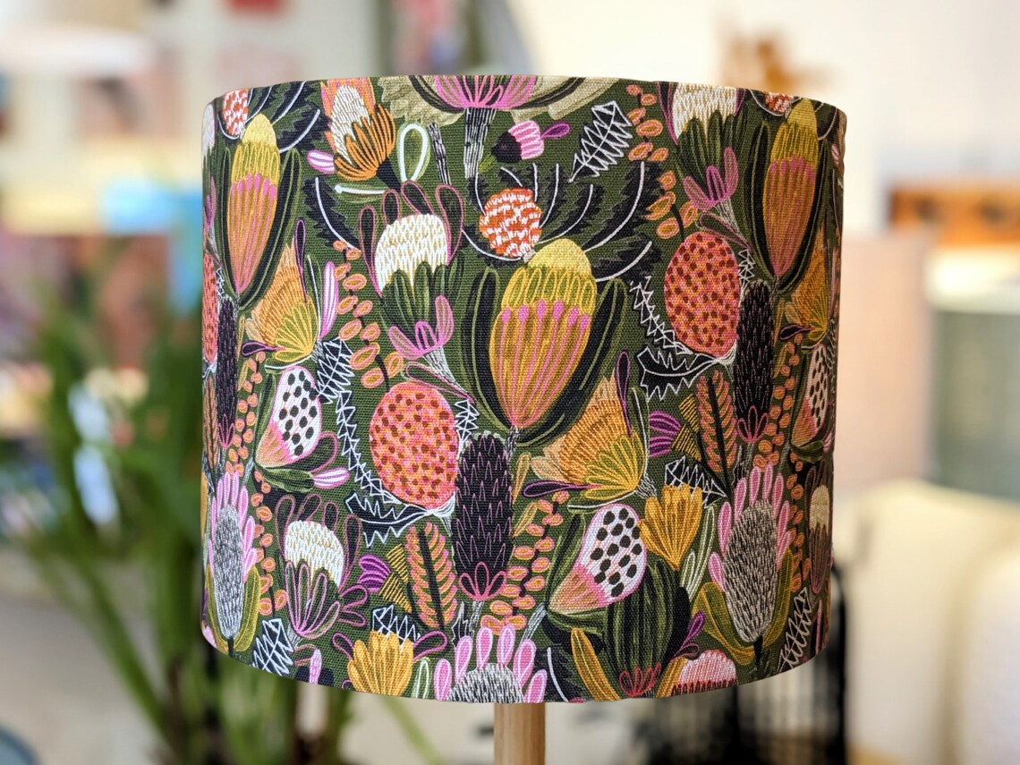 Handmade Bush Banksia lampshade by Emotive Collection, featuring a stunning design by Australian artist Jocelyn Proust. The lampshade showcases vibrant Banksia flowers on a green background. Crafted with care in Australia.