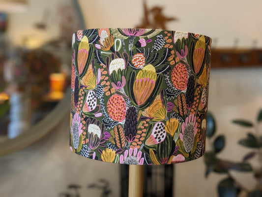 Handmade Bush Banksia lampshade by Emotive Collection, designed by Australian artist Jocelyn Proust. Featuring vibrant Banksia flowers on a lush green background, crafted with care in Australia.