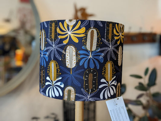 Handmade Midnight Banksia lampshade by Emotive Collection, featuring elegant Banksia flowers on a dark background. Designed by Australian artist Jocelyn Proust, this lampshade adds a touch of sophistication and nature to any room. Expertly crafted in Aust