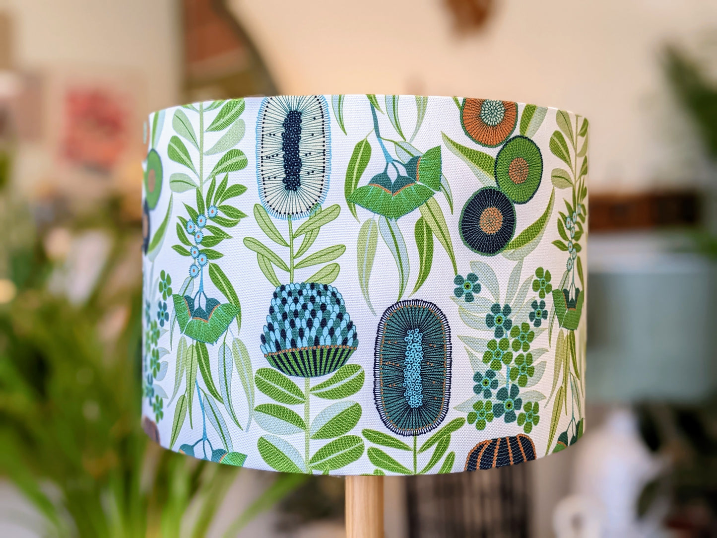 The Green Australiana Lampshade by Emotive Collection features a vibrant pattern of green leaves and abstract florals in blue, teal, and olive—an eye-catching Australian made design.