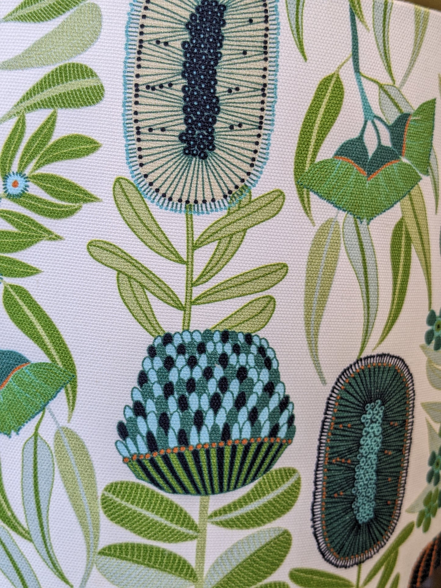 A close-up of the Emotive Collections Green Australiana Lampshade shows embroidered botanical patterns with abstract green leaves and blue-teal flowers on white—a Jocelyn Proust-inspired design, perfect for Australian-made decor.