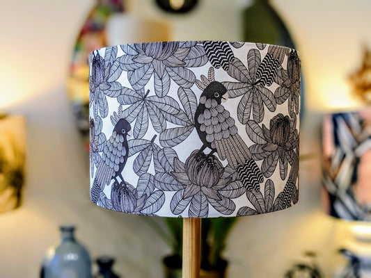The Emotive Collection’s Australian Cockatoo Lampshade features a handmade black and white botanical and bird design, with detailed leaves and cockatoos in focus, while softly blurred decor accents the background.