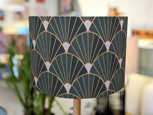 A close-up of the Art Deco Lampshade (35cm x 24cm) by Art Deco, showcasing a vintage geometric pattern in dark green, gold, and white, set against a blurred indoor backdrop.