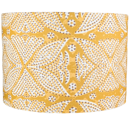 The Leela Indian Block Print Lampshade by 100% Premium Linen is a drum-shaped, handcrafted linen shade, featuring yellow fabric with white and brown geometric dot and floral patterns.
