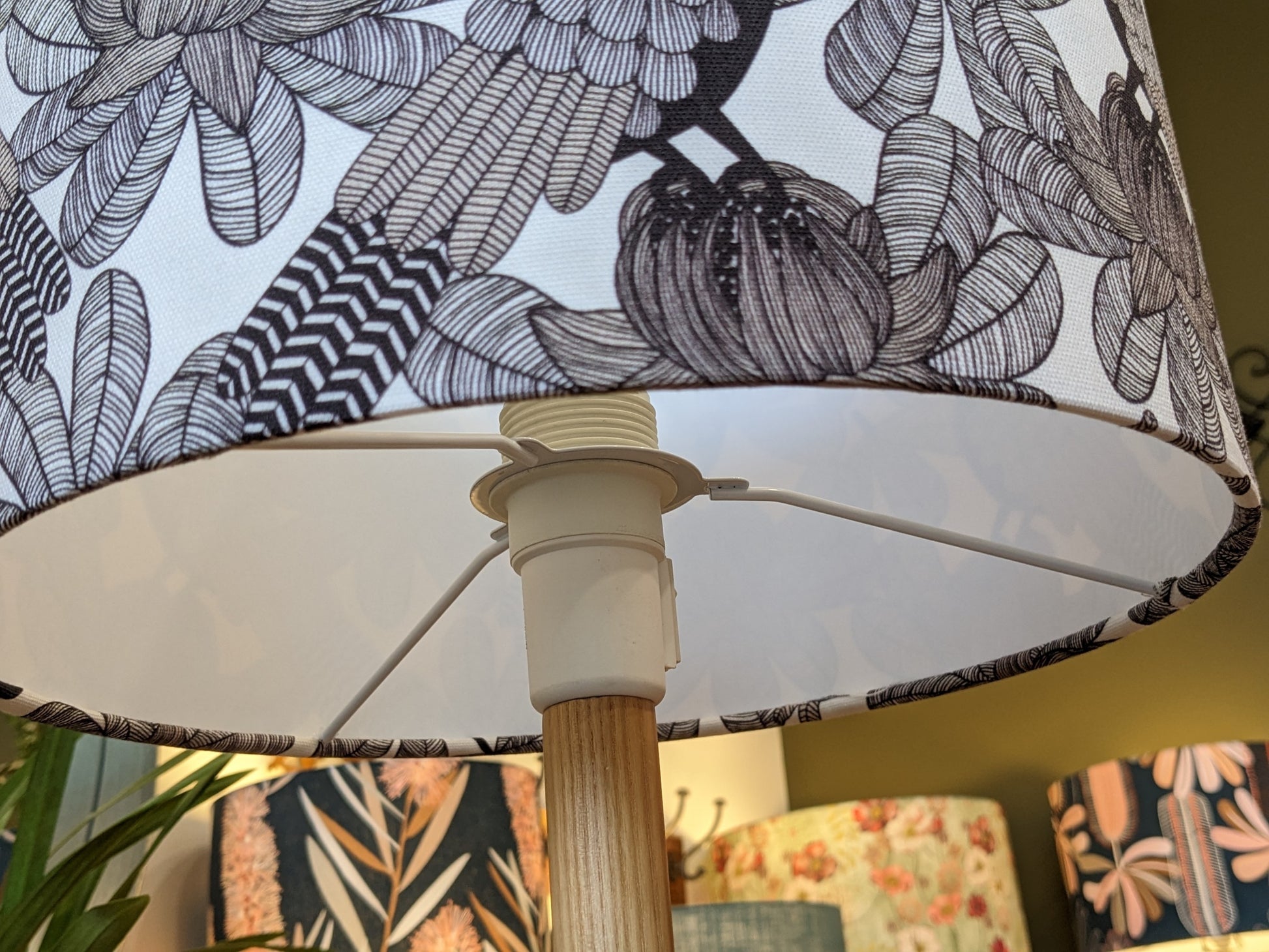 Close-up of the Emotive Collection’s Australian Cockatoo Lampshade, featuring a handmade black and white floral design on a wooden base. Other lamps with abstract prints by this Australian designer are softly blurred in the background.