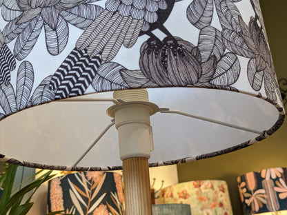 Close-up of the Emotive Collection’s Australian Cockatoo Lampshade, featuring a handmade black and white floral design on a wooden base. Other lamps with abstract prints by this Australian designer are softly blurred in the background.